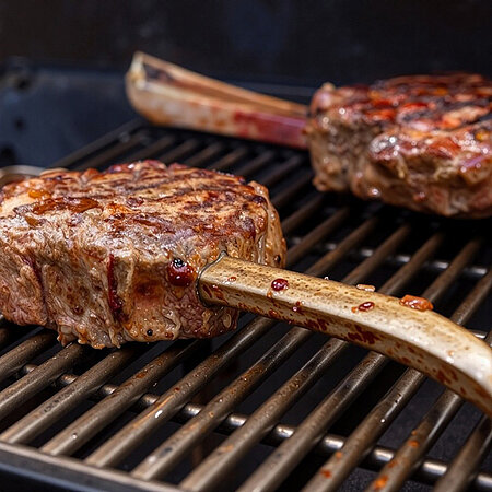 Zwei Rippchen auf einem Grill. Sie sind bereits gut durchgegart und bereit zum Verzehr.